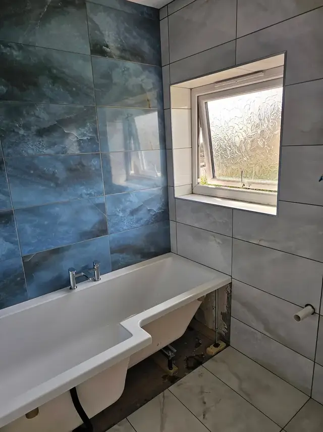 Bathroom with a blue marble-effect tiled feature wall above a bath