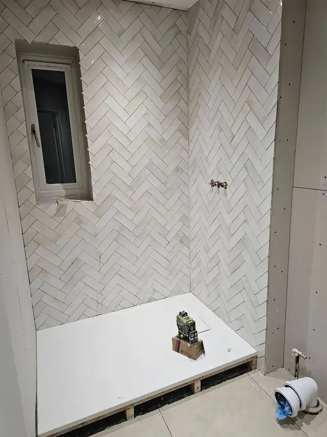 Herringbone wall tiles in a walk-in shower with a white shower tray