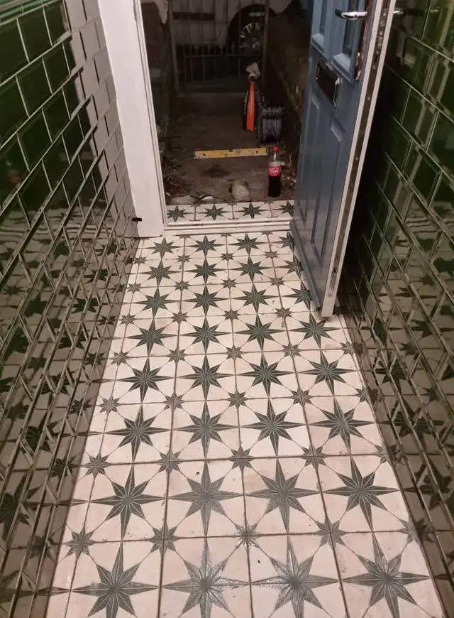 Star pattern floor tiles in a hallway with green wall tiles