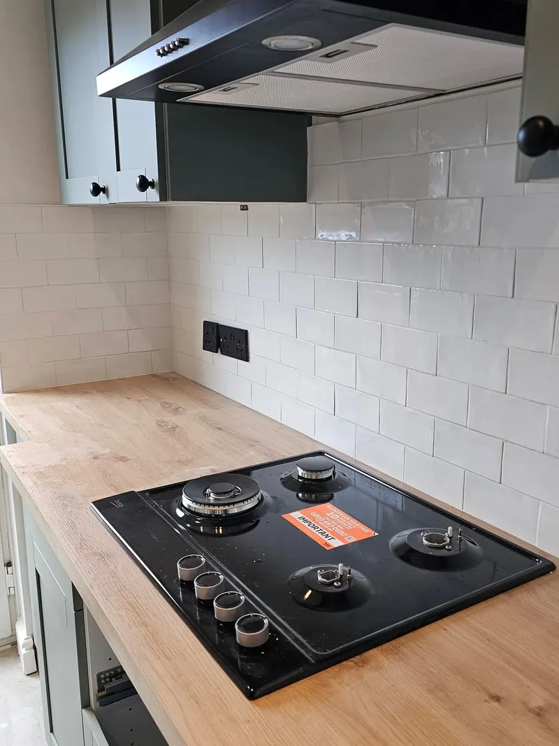 White brick-effect kitchen splashback above a wooden worktop and black hob