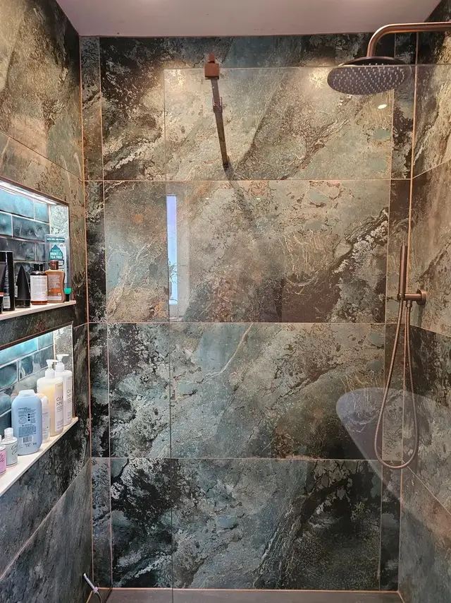 Shower wall tiled in large green and black marble-effect porcelain tiles