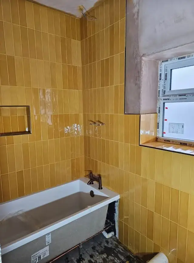 Mustard yellow glazed wall tiles around a bath