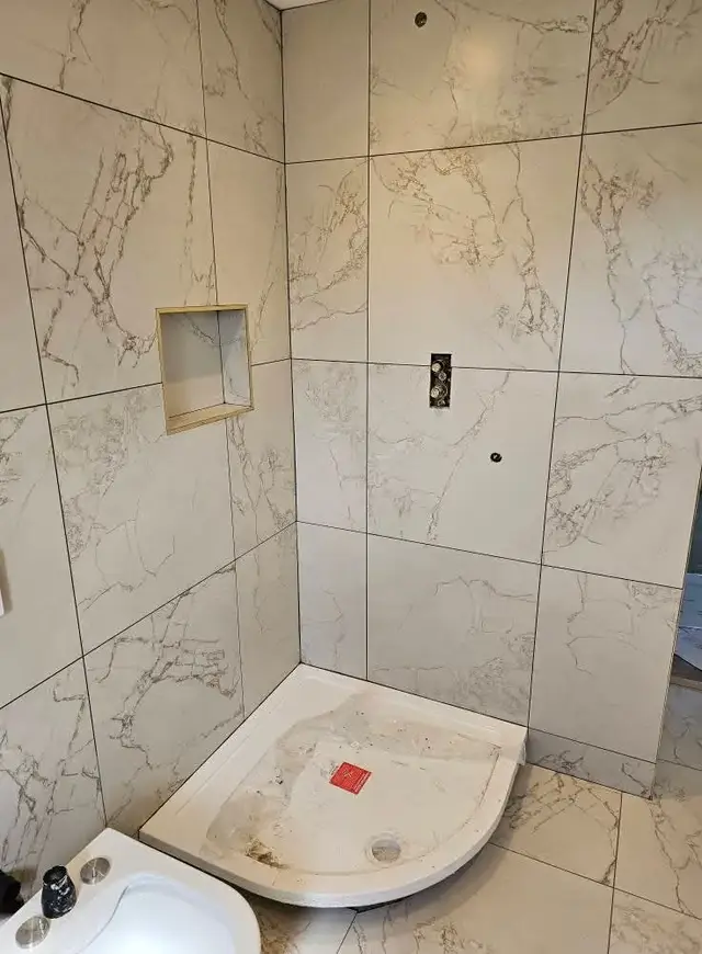 White marble-effect shower walls with a tiled shelf