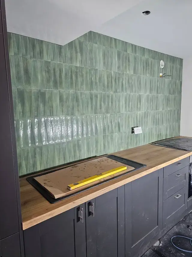 Green glazed kitchen splashback above a wooden worktop