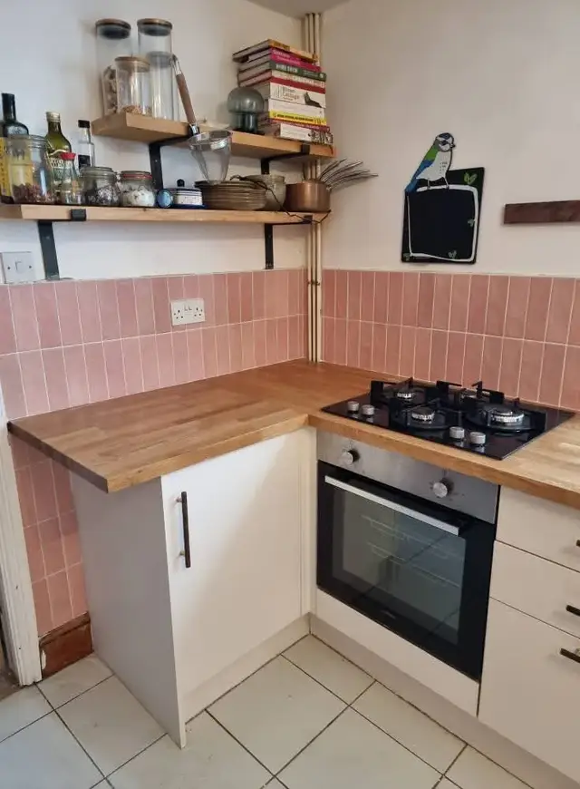 Pink tiled kitchen splashback with a wooden worktop